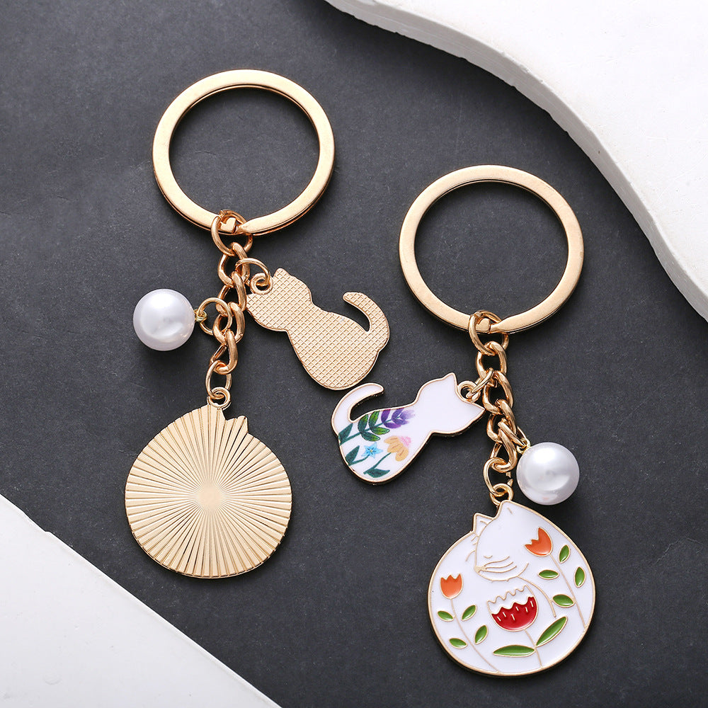 Wholesale oil drop cartoon cute flowers white cat pearl keychain metal jewelry pendant manufacturers